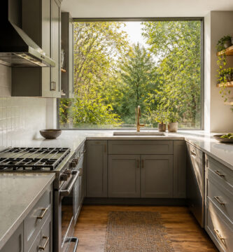A stylish U-shaped kitchen featuring light wood cabinets and bright countertops.